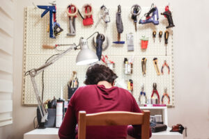 Maker is working on his workshop table with his tools and pieces